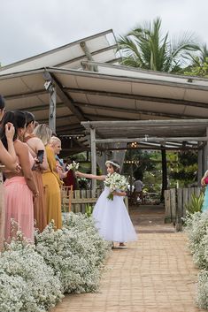 the bride is walking down the aisle with her bouquet in hand and other people behind her