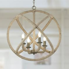 a chandelier hanging from a ceiling with rope wrapped around it and three candles in the center