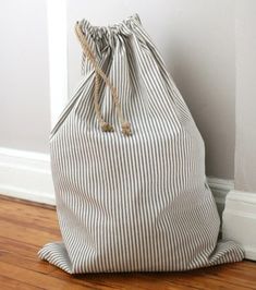 a striped bag sitting on the floor next to a white wall and wood flooring