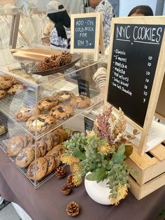 a table topped with lots of pastries next to a chalkboard sign that says nyc cookies