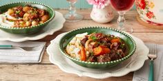 two bowls filled with food sitting on top of a wooden table next to silverware