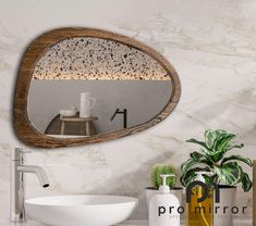 a bathroom sink sitting under a mirror next to a potted plant and vases