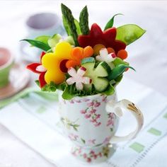 a cup filled with colorful flowers on top of a table