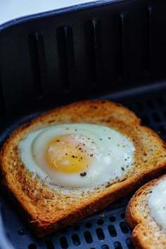 two pieces of bread with an egg in the middle on top of them, sitting on a grill