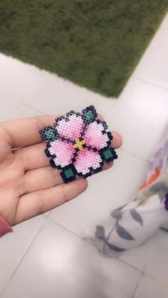 a hand holding a small pink flower brooch