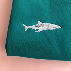 a green t - shirt with a shark embroidered on it