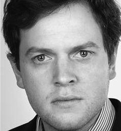 a black and white photo of a man wearing a suit with a striped shirt on