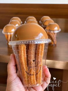 a person holding up a plastic cup filled with churros