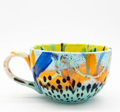 a colorful coffee cup sitting on top of a white table