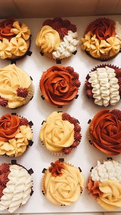 twelve cupcakes in a white box with orange and yellow frosting flowers on them