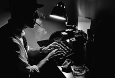 a man sitting at a desk typing on an old fashioned typewriter in the dark