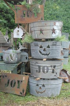 an assortment of metal buckets are stacked on top of each other in the grass