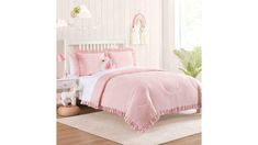 a bed with pink comforters and pillows on top of it in a white room