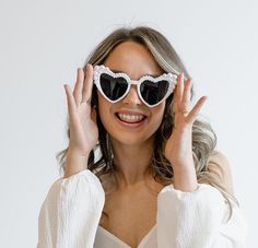 a woman wearing heart shaped sunglasses holding her hands up