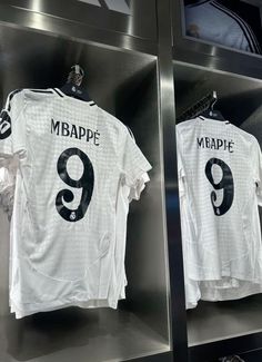 two soccer jerseys are on display in the locker room, one is white and the other is black