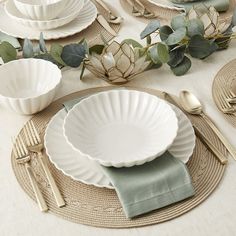 a place setting with plates, silverware and greenery