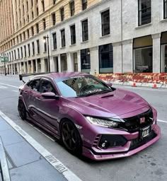 a purple car is parked on the side of the road in front of some buildings