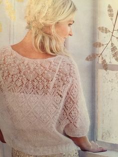 a woman standing in front of a window wearing a white sweater and gold sequin skirt