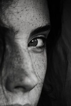 a woman with freckles on her face looking at the camera while she's close up