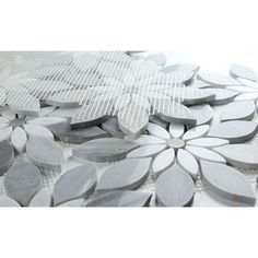 white and grey flowers are arranged on the floor in this mosaic tile design that is part of a wall