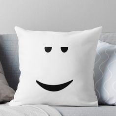 a white pillow sitting on top of a couch next to a gray throw pillow with black eyes