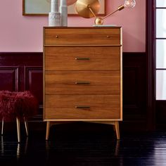 a chest of drawers in a room with pink walls and wooden flooring on the side