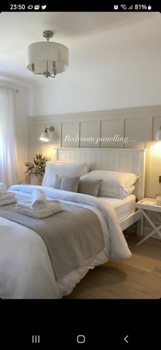 a white bed sitting in a bedroom next to a window with curtains and pillows on top of it