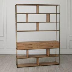 a wooden shelf with drawers and shelves on the bottom, against a white wall in an empty room