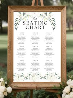 a seating chart with white flowers and greenery on the side is displayed in front of an easel