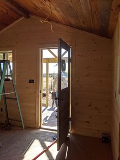 the inside of a house being built with wood and glass on the door, windows in the wall