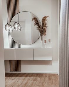 there is a mirror on the wall in this bathroom with wood flooring and white walls