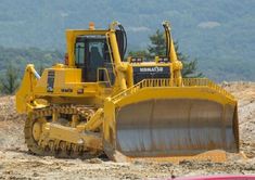 a large yellow bulldozer sitting on top of a dirt field