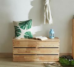 a wooden box with a book and some plants on it sitting next to a lamp