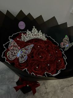 there is a black plate with red roses and butterflies on it, along with two butterfly brooches