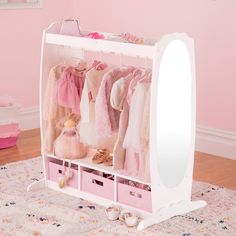 a child's closet with pink drawers and clothes hanging on the wall next to a mirror