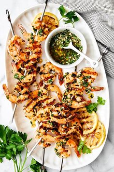 grilled shrimp skewers with cilantro sauce on a white platter