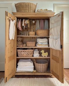 an open closet with baskets, clothes and blankets in the door is filled with linens