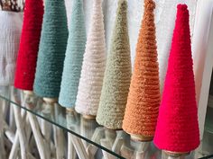 a row of knitted christmas trees sitting on top of a glass shelf