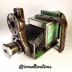 an old, rusty camera sitting on top of a white table next to a screwdriver