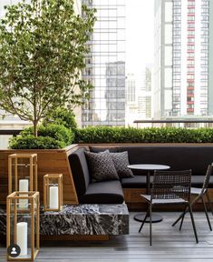 an outdoor seating area with chairs, tables and plants on the roof deck in front of high rise buildings