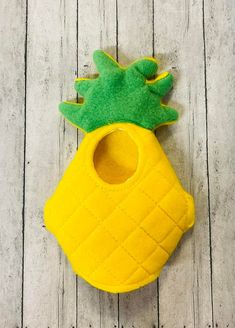 a yellow pot holder with a green pineapple on it's side, sitting on a wooden surface