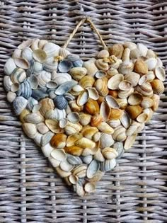 a heart made out of shells hanging on a wicker wall ornament in the shape of a heart