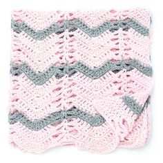 a pink and gray crocheted blanket on top of a white surface with an arrow in the middle