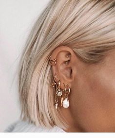 a woman with blonde hair wearing gold ear cuffs and pearl drop earrings on her left ear