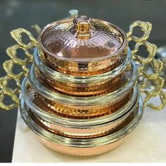 a stack of gold and silver dishes sitting on top of each other