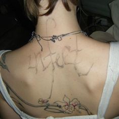 the back of a woman's neck with writing on it and flowers all over her chest