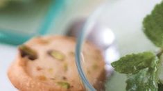 a close up of a cookie on a table with mint sprig in the foreground