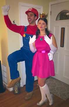 a man and woman dressed up as mario and luigi in front of a door,