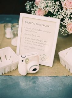 there is a polaroid guest book next to some baby's breath bottles and flowers