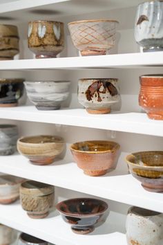 many bowls are sitting on shelves in a room